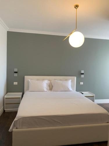 a bedroom with a large white bed with a lamp at Royal apartament in Durrës