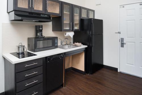 a kitchen with black cabinets and a sink and a microwave at Candlewood Suites Olympia - Lacey by IHG in Lacey