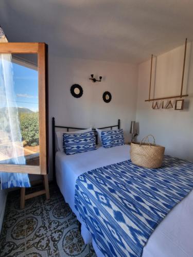 a bedroom with a bed with a blue comforter and a window at Eco Finca Sa Font Blava in Llucmajor