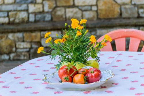 eine Schale mit Obst und Blumen auf dem Tisch in der Unterkunft Σπίτι στο Τείχιο με θέα Βαρδούσια και Γκιώνα in Tíkhion