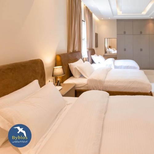 een hotelkamer met 3 bedden met witte lakens bij Byblos Villa Resort in Al Ḩadd