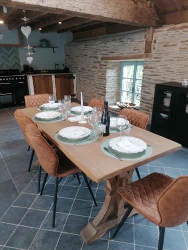 a wooden table with plates and wine glasses on it at La Maison de Madeleine in Léglise