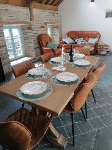 a wooden table with plates and wine glasses on it at La Maison de Madeleine in Léglise
