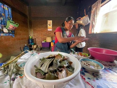 a woman standing in a kitchen with a bowl of food at LÍZU Tu casa en un pueblo zapoteca in Teotitlán del Valle