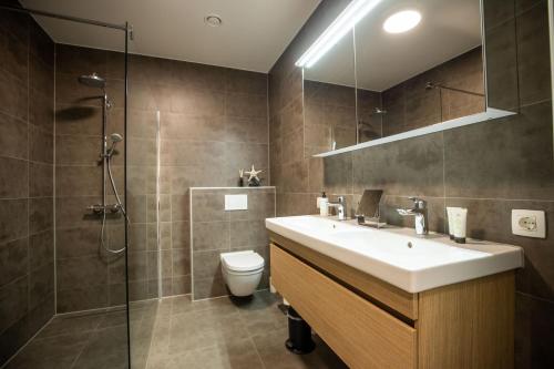a bathroom with a sink and a shower and a toilet at The Lagune, light and sunny apartment in the dunes in Cadzand
