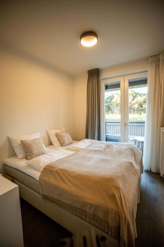 a bedroom with a large bed in front of a window at The Lagune, light and sunny apartment in the dunes in Cadzand