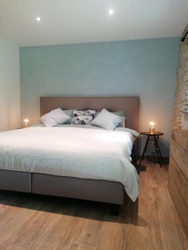 a bedroom with a large bed with two candles on it at La Maison de Madeleine in Léglise