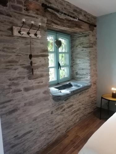 a room with a stone wall and a window at La Maison de Madeleine in Léglise