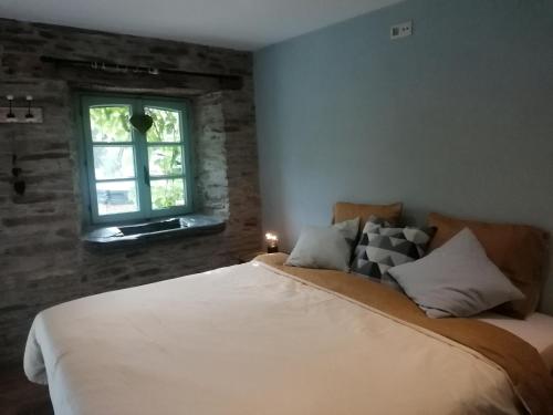 a bedroom with a large bed and a window at La Maison de Madeleine in Léglise