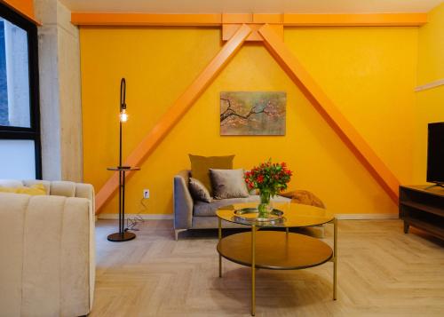 uma sala de estar com paredes amarelas e uma mesa com flores em Roma Majestic By Mr W em Cidade do México