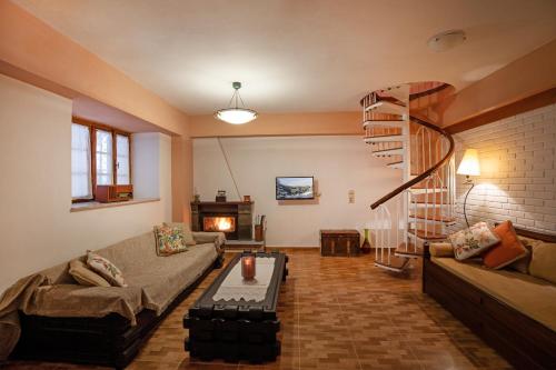 a living room with a couch and a spiral staircase at Kallisti Vitina Home in Vitina