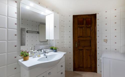 a white bathroom with a sink and a mirror at Kallisti Vitina Home in Vitina