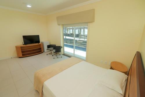 a bedroom with a bed and a tv and a window at ALIZE CUMBUCO in Cumbuco