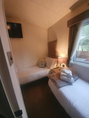 a small room with two beds and a window at Chillingham lodge with hot tub Felmoor Park in Felton