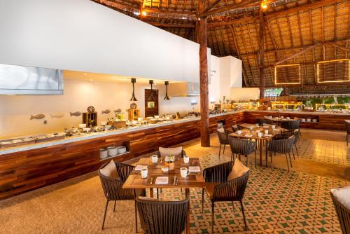 ein Restaurant mit Tischen und Stühlen und eine Bar in der Unterkunft Presidente InterContinental Cozumel Resort & Spa by IHG in Cozumel