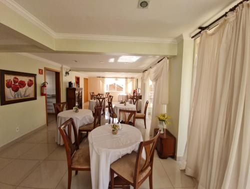 un comedor con mesas y sillas con manteles blancos en Novo Grande Hotel, en Ribeirão Preto