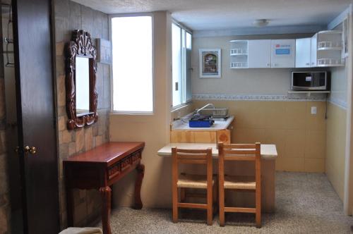 una pequeña cocina con fregadero, mesa y sillas en Santa Ana Suites & Lofts, en Toluca