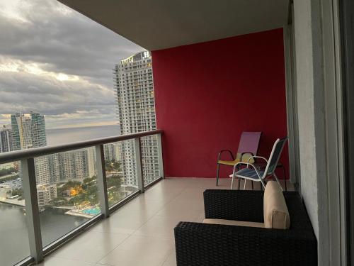 a balcony with a red wall and chairs on a balcony at Stunning Penthouse Suite Waterfront 2BD 2BA in Hallandale Beach