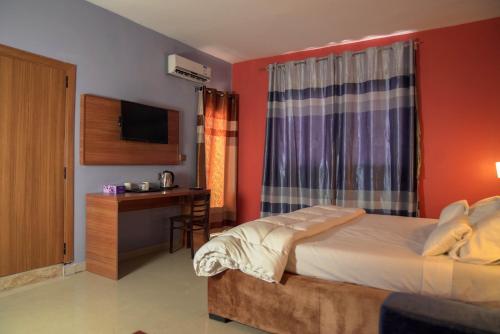 a bedroom with a bed and a desk and a television at Dialali Hôtel Nouakchott in Nouakchott