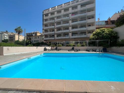 une grande piscine bleue en face d'un bâtiment dans l'établissement Studio piscine proche plage et palais des festivals cannes banane, à Cannes