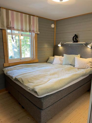 a large bed in a bedroom with a window at Cozy cabin, neighbour to lake & national park in Tyresö