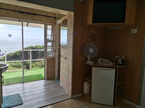 a bathroom with a sliding glass door with a view of the ocean at On the Rocks Guesthouse in Gansbaai