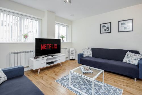 a living room with a blue couch and a tv at MPL Apartments - Queens Broadway F3 in Watford