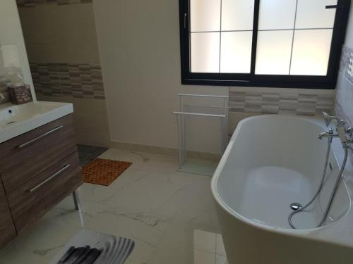 a white bathroom with a tub and a sink at Villa Marie in Graignes
