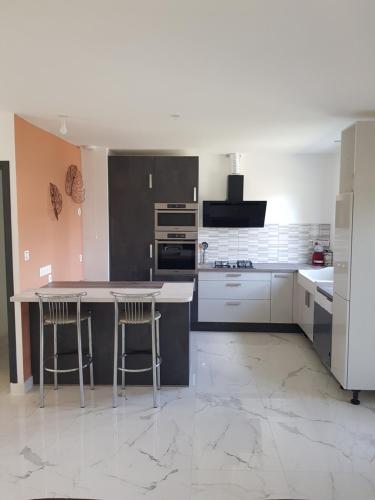 - une cuisine avec une table et quelques tabourets dans l'établissement Villa Marie, à Graignes