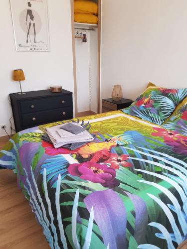 a bed with a colorful comforter on top of it at Villa Marie in Graignes