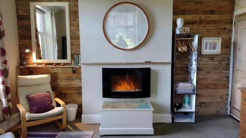 a living room with a fireplace and a mirror at The Cabin: Great Views,Garden,Close to Town, Quiet in Hebden Bridge