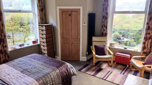 a bedroom with a bed and a chair and windows at The Cabin: Great Views,Garden,Close to Town, Quiet in Hebden Bridge