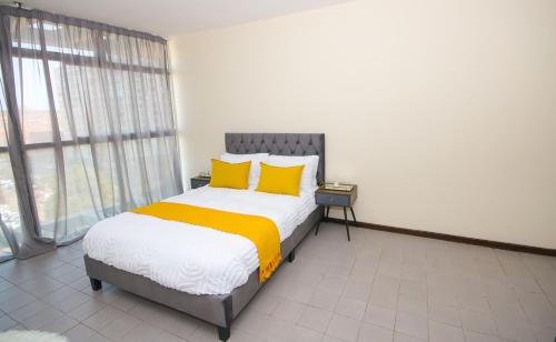 a bedroom with a large bed with yellow pillows at 10South in Durban