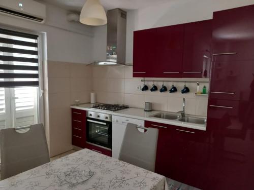 una cocina con armarios rojos y fregadero en Apartman Felice, en Kraljevica