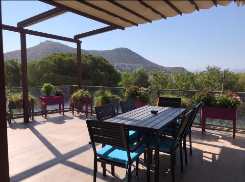 een tafel en stoelen op een patio met bergen op de achtergrond bij Leman Apart in Bodrum City