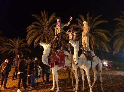 a group of people riding on camels on the beach at Hotel Pansy in Ksar Ghilane