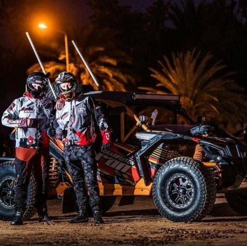 two people are standing next to a four wheeled vehicle at Hotel Pansy in Ksar Ghilane