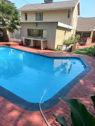 a swimming pool with a hose in front of a house at 26 Zea avenue Arcon Park Guest House in Vereeniging