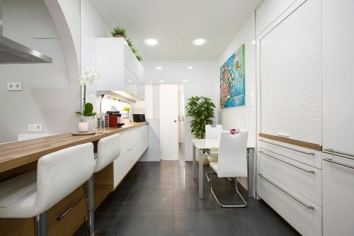a kitchen with white cabinets and a table and chairs at HABITACION EN VIVIENDA GRAN VIA BILBAo in Bilbao