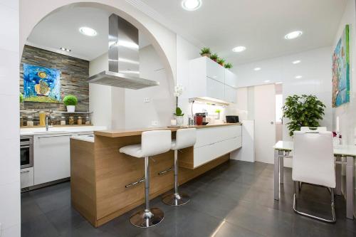 eine Küche mit weißen Schränken und einer Theke mit Stühlen in der Unterkunft HABITACION EN VIVIENDA GRAN VIA BILBAo in Bilbao
