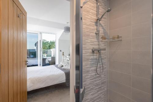 a bathroom with a walk in shower next to a bed at Rutland Heights,A Fantastic Modern Coastal House, Sea Views, Garden, Terraces, 2x Allocated Private Parking Spaces plus Free Private use of Electric Vehicle Point Meadfoot Beach only 5mins away! Also Shops, Bars and Restaurants just a 10 minute walk! in Torquay