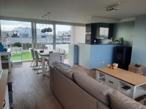 a living room and kitchen with a couch and a table at Penthouse VI in Koksijde