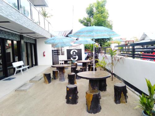 a group of tables and stools with umbrellas at Strangers Inn&Bar in General Luna
