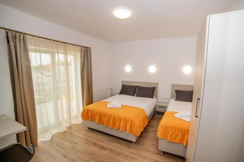two beds with orange sheets in a room with a window at Pensiunea Zbor in Cluj-Napoca