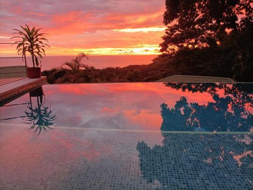 una piscina con puesta de sol en el fondo en Vista Naranja Ocean View House, en Mal País