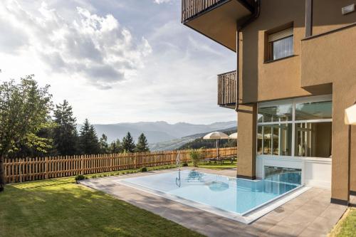 una casa con piscina en un patio en Hotel Baumwirt en Castelrotto
