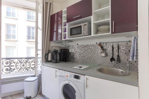 une cuisine avec une machine à laver et un évier dans l'établissement RASPAIL Cozy Flat, à Paris
