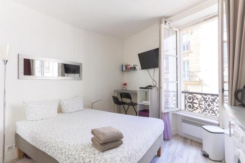 een witte slaapkamer met een bed en een raam bij RASPAIL Cozy Flat in Parijs