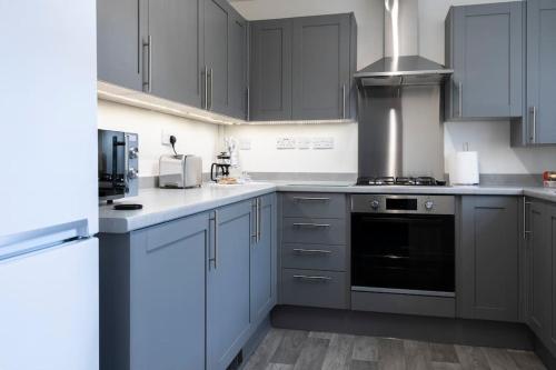 a kitchen with gray cabinets and a stove top oven at Fair Haven - Off Street Parking and Garden in Shrewsbury