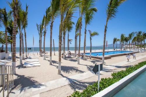 a beach with palm trees and a swimming pool at Estudio 573 Nuevo Vallarta, frente al mar, equipado y amueblado ! in Nuevo Vallarta